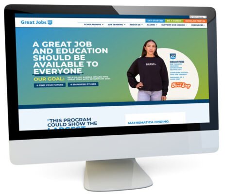 The computer monitor showcases the Great Jobs KC website, expertly crafted by a talented web designer. The main text promotes job and education goals, featuring an image of a person in a "Brave." sweatshirt. Various navigation options are neatly arranged at the top.